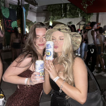Two women holding Ape Water samples at an event
