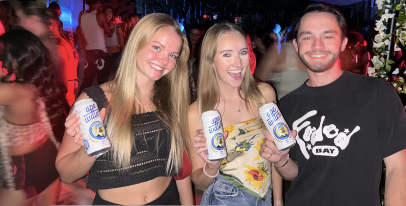 Three attendees holding Ape Water beverage samples