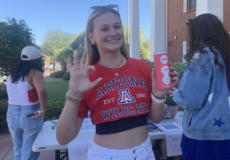 Student holding a promotional beverage sample outdoors